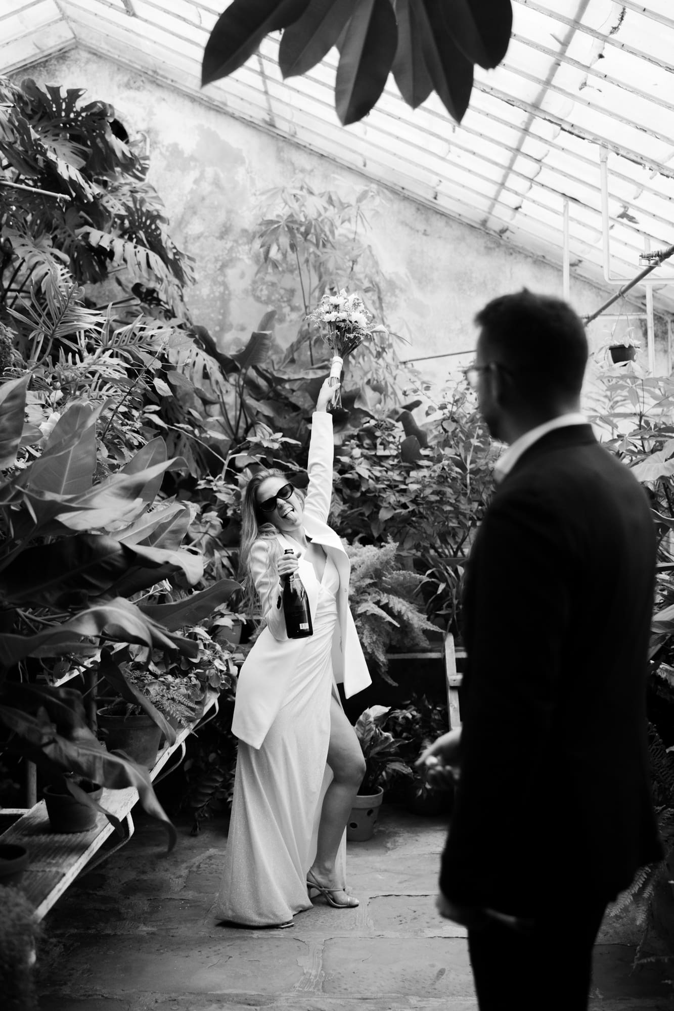 Bride exploring the tropical greenhouse at Villa Mirasasso while her groom watches from afar.