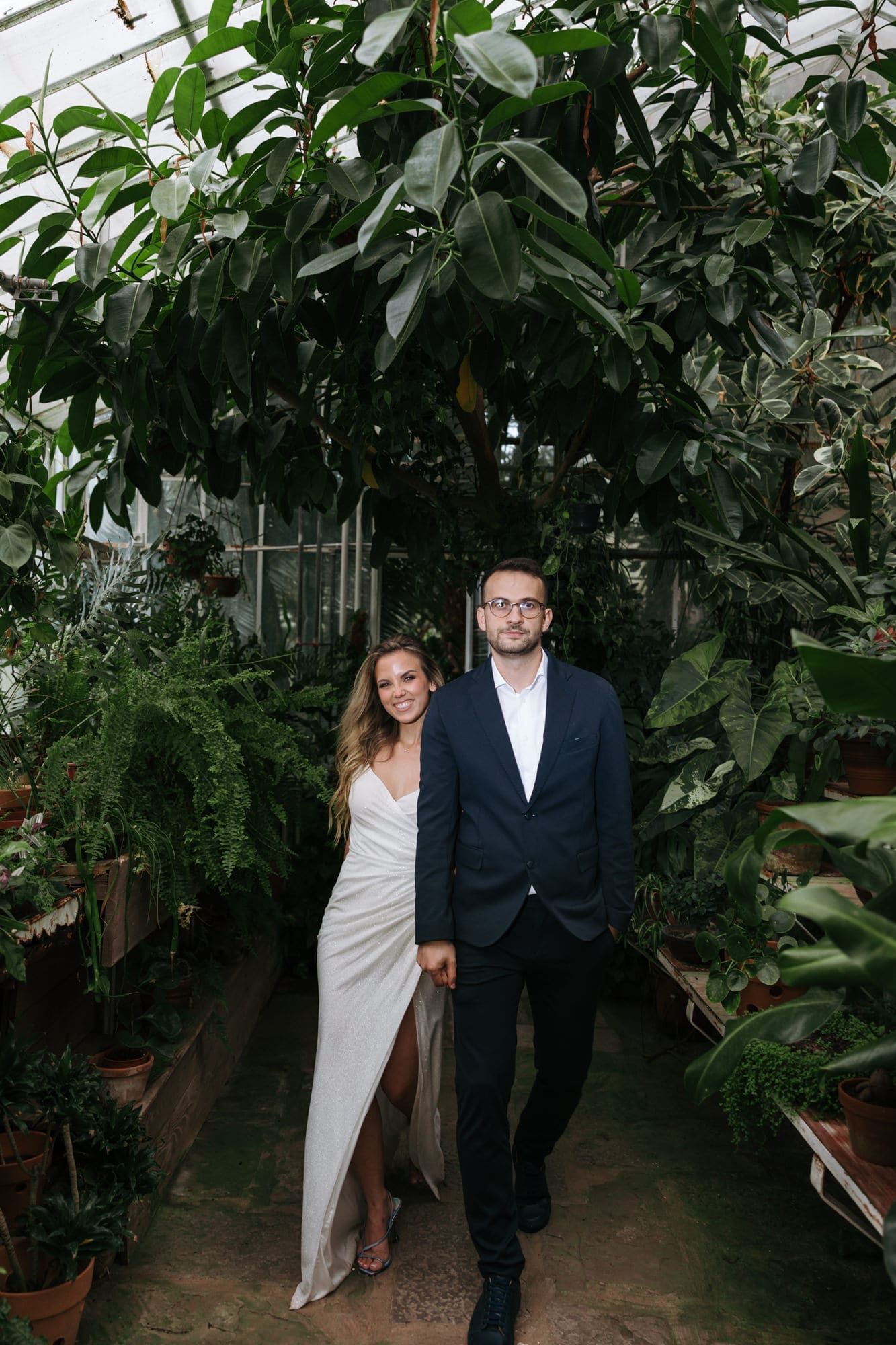 Bride and groom walking through the lush tropical greenhouse at Villa Mirasasso near Sežana, Slovenia.