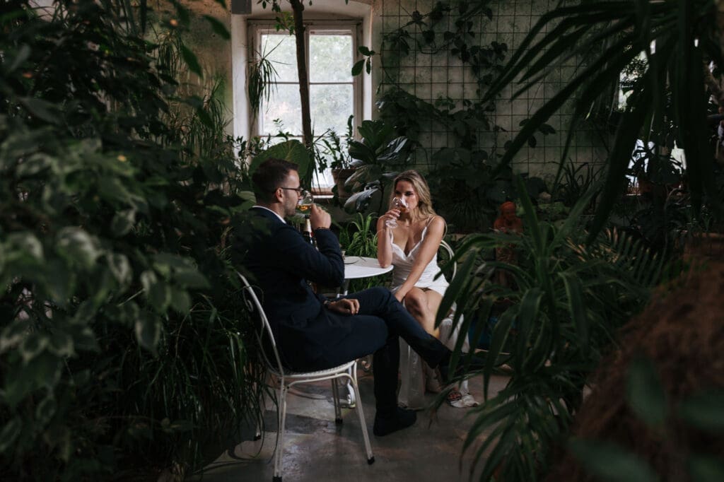 Bride and groom sharing a quiet moment surrounded by tropical plants inside Villa Mirasasso's historic greenhouse.